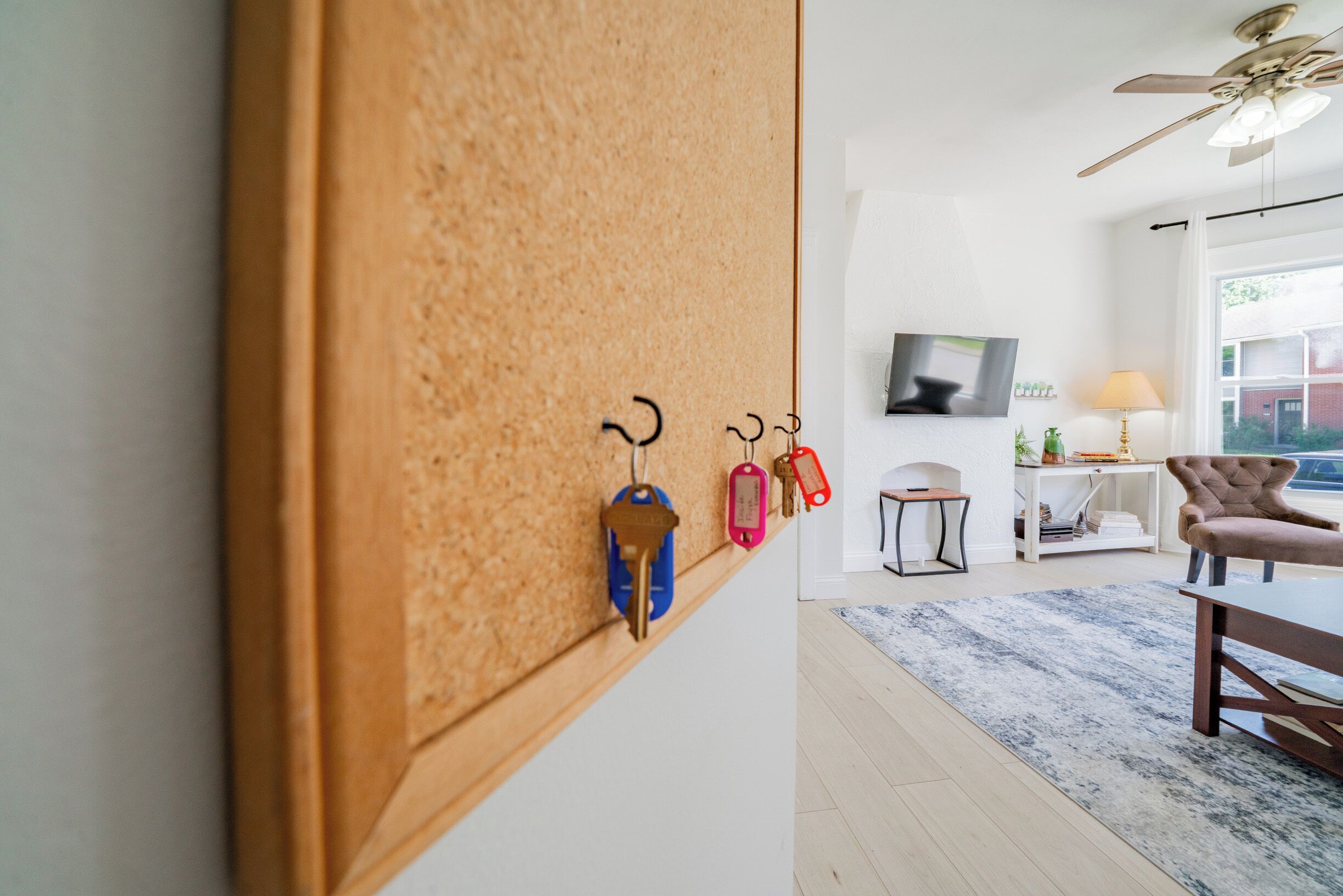 A modern living room with a corkboard wall, a television, a lamp, and a chair.