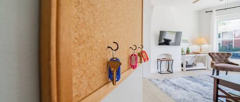 A modern living room with a corkboard wall, a television, a lamp, and a chair.