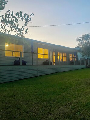 A single-story house with a porch, large windows, and a lawn. - “Southerly Change”.
Groovy retro/modern Beach House.
Bring your surfboard & dog! (Moruya Heads)