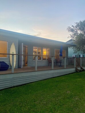A house with a covered porch, a surfboard leaning against the wall, and a tree in the background. - “Southerly Change”.
Groovy retro/modern Beach House.
Bring your surfboard & dog! (Moruya Heads)