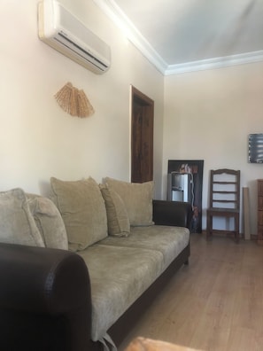 A living room with a sofa, a chair, a wooden cabinet, and a mounted air conditioner. - Moonlight terrace  (Fethyie)