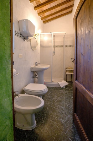 A bathroom with two toilets, a sink, a shower, and a wooden door. - Toskana Family Home With Pool (Siena)