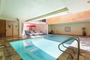 Ein Hallenbad mit Liegestühlen und einem roten Sonnenschirm.
