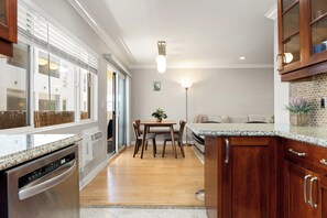 Une cuisine moderne avec des meubles en bois, un four encastré et un coin repas comprenant une table et des chaises.