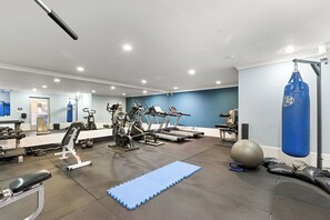 Une salle de sport équipée de tapis de course, d’appareils de musculation et d’un sac de frappe.