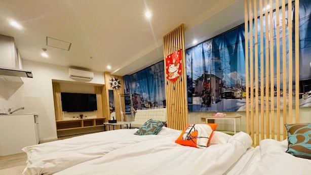 A hotel room with two beds, a TV, a desk, and a large window with a cityscape view. - Toei Stays (Nipponbashi Higashi, Naniwa-ku osaka)