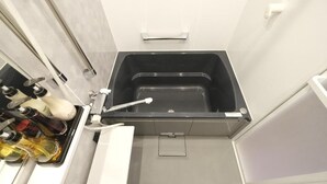 A bathroom with a black bathtub, a white sink, and a mirror. - Toei Stays (Nipponbashi Higashi, Naniwa-ku osaka)