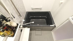 Ein Badezimmer mit einer schwarzen Badewanne, einem weißen Waschbecken und einem Spiegel.