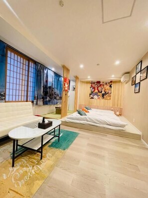Ein modernes Schlafzimmer mit Bett, Sofa, einem kleinen Tisch und einem großen Fenster mit Blick.