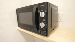 Eine schwarze Mikrowelle auf einer Holzablage mit Leistungseinstellungen und einem Aufkleber, der 700W angibt.