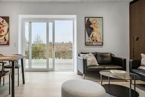Ein modernes Wohnzimmer mit Essbereich, einem Glastisch und einer Couch.