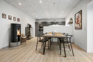 Eine moderne Küche mit Kochinsel, Essbereich mit Stühlen, Einbauherd und Kühlschrank.