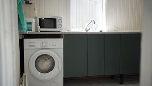Ein kleiner Waschbereich mit Waschmaschine, Mikrowelle und Spüle.