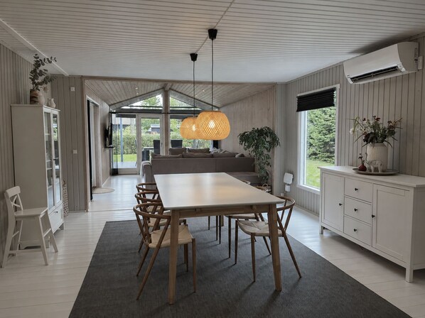 Een moderne keuken met een eethoek, met een grote tafel, stoelen en een hanglamp.