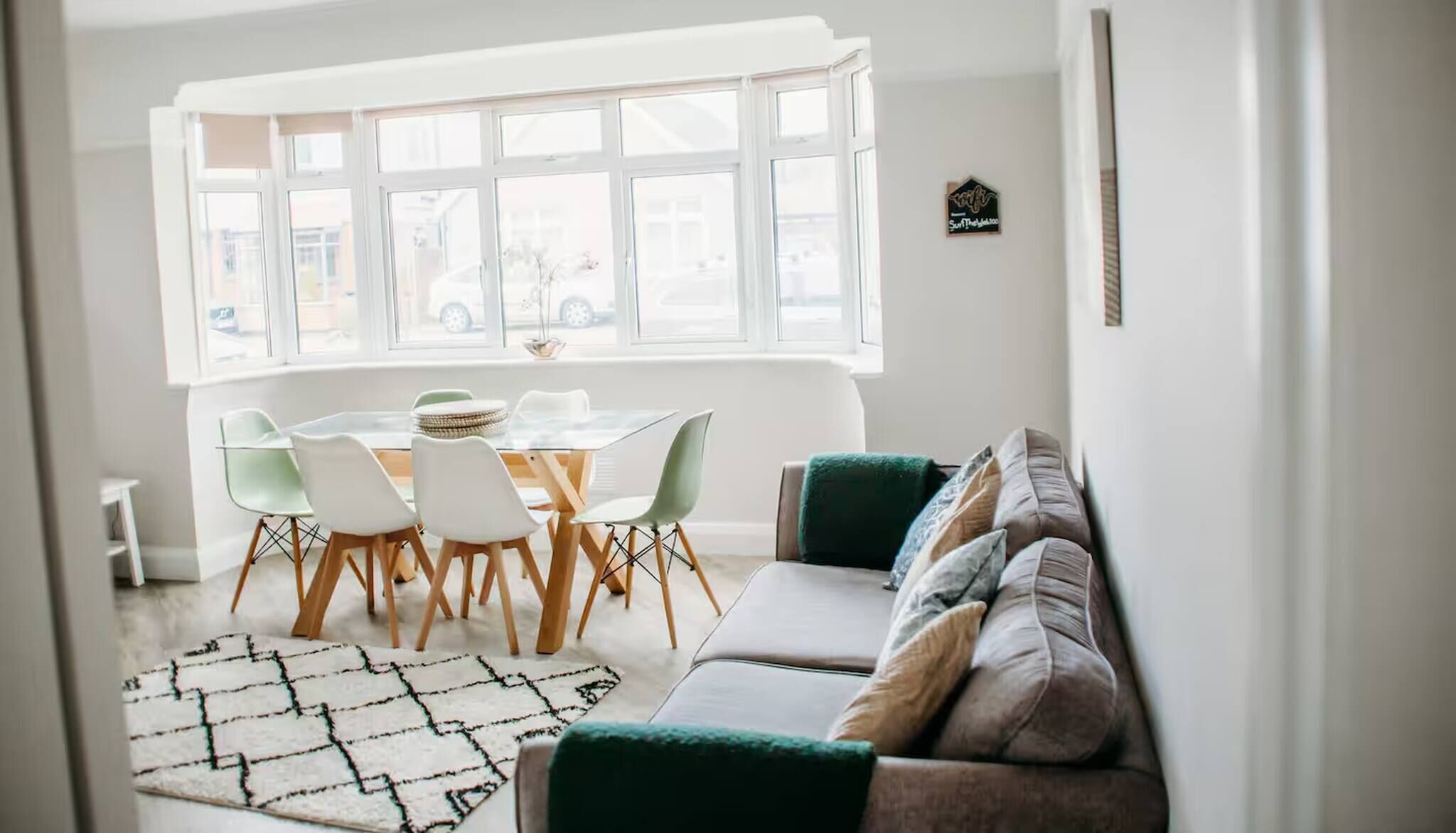 A dining area with a round table and chairs, a sofa, and a patterned rug.