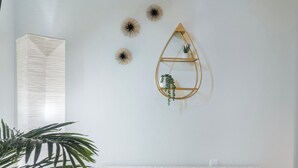 Una habitación con un banco de madera, una estantería con una planta y decoración en la pared.