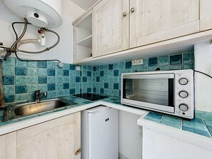 Een kleine keuken met een magnetron, een spoelbak en een kleine koelkast.