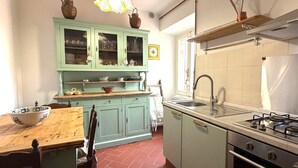 Una cucina con un tavolo di legno, sedie, un lavandino, un fornello e mobili verdi chiaro.
