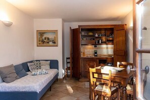 Ein kompakter Wohnbereich mit Sofa, Esstisch und offener Küchenzeile mit Geschirr.