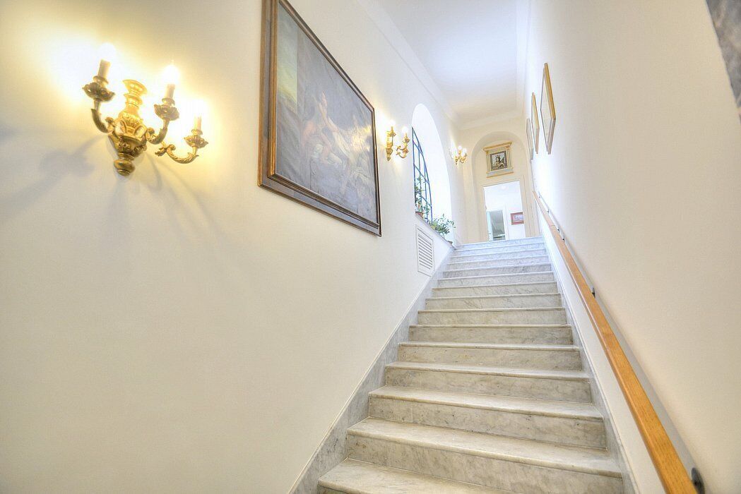 A marble staircase with wall sconces and a framed painting.