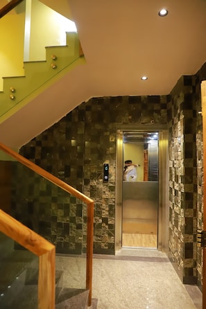 Un interior moderno con una escalera, un ascensor y paredes con textura.