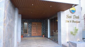 A building entrance with a wooden overhang, a large wooden door, and a sign that reads 'Sea Duck Bed & Breakfast.' - Sea Deck (Port Blair)