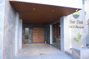 A building entrance with a wooden overhang, a large wooden door, and a sign that reads 'Sea Duck Bed & Breakfast.' - Sea Deck (Port Blair)