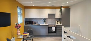 Una cocina compacta con gabinetes blancos, microondas, tostadora y lavamanos.