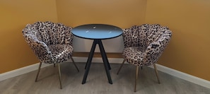 A corner with two leopard print chairs and a small round table.