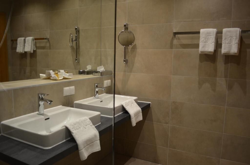 Un baño moderno con dos lavamanos, un espejo grande y una cabina de ducha de vidrio.