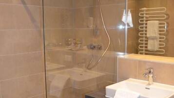 Ein modernes Badezimmer mit einer Duschkabine, einem Waschbecken mit Handtuch und einem Spiegel darüber.