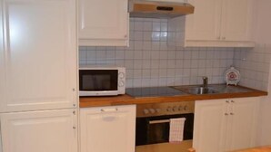 A kitchen with white cabinets, a microwave, an oven, and a wooden dining table.