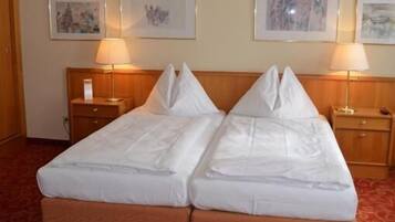 Una cama doble con cabecera de madera, dos mesitas de noche con lámparas y una alfombra roja con estampado.