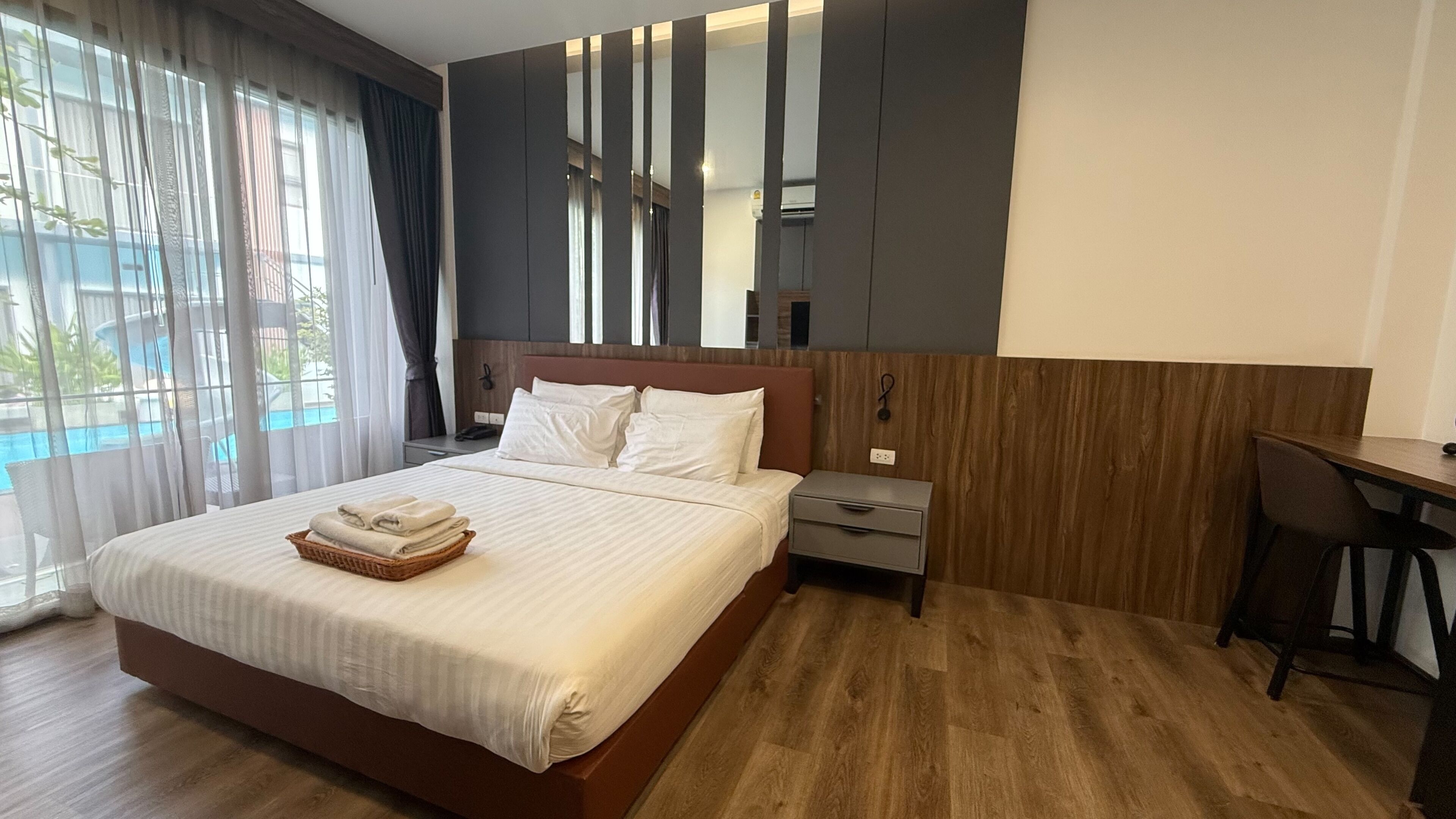 Ein Hotelzimmer mit einem großen Bett, einem Schreibtisch und Blick auf einen Pool.