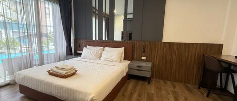 Ein Hotelzimmer mit einem großen Bett, einem Schreibtisch und Blick auf einen Pool.