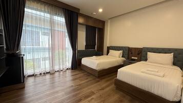 Habitación de hotel con dos camas, televisión y un ventanal con cortinas.