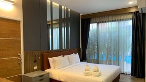 A hotel room with a bed, bedside table, nightstand, and a view of the outdoors. - The River Kwai Bridge Resort 2 (Kanchanaburi)