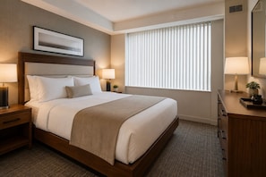 A hotel room with a bed, bedside lamps, a nightstand, a dresser, a mirror, and a window with blinds. - Harborlight Suites (Toronto)
