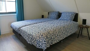 A bedroom with a bed, a window with curtains, a bedside table, and a speaker. - Holiday Home in Uitdam With Wi-fi (Uitdam)