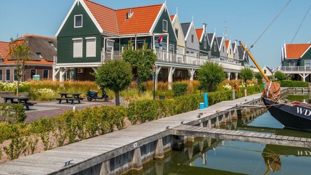 A row of traditional houses with red roofs, a wooden dock, and a boat named 'WD' docked at the pier. - Holiday Home in Uitdam With Wi-fi (Uitdam)