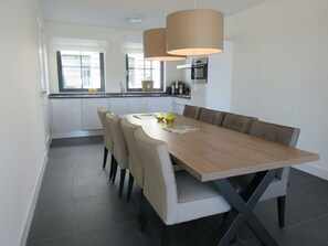 Eine moderne Küche mit weißen Schränken, einem Holztisch und zwei Pendelleuchten.