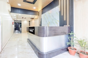 A reception desk with a marble floor, a wooden ceiling, and potted plants.