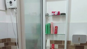 A small bathroom with a toilet, shower, and a glass door leading to a tiled area.