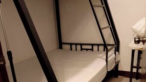 A bunk bed with a ladder, a small table with a lamp, and a door leading to another room.