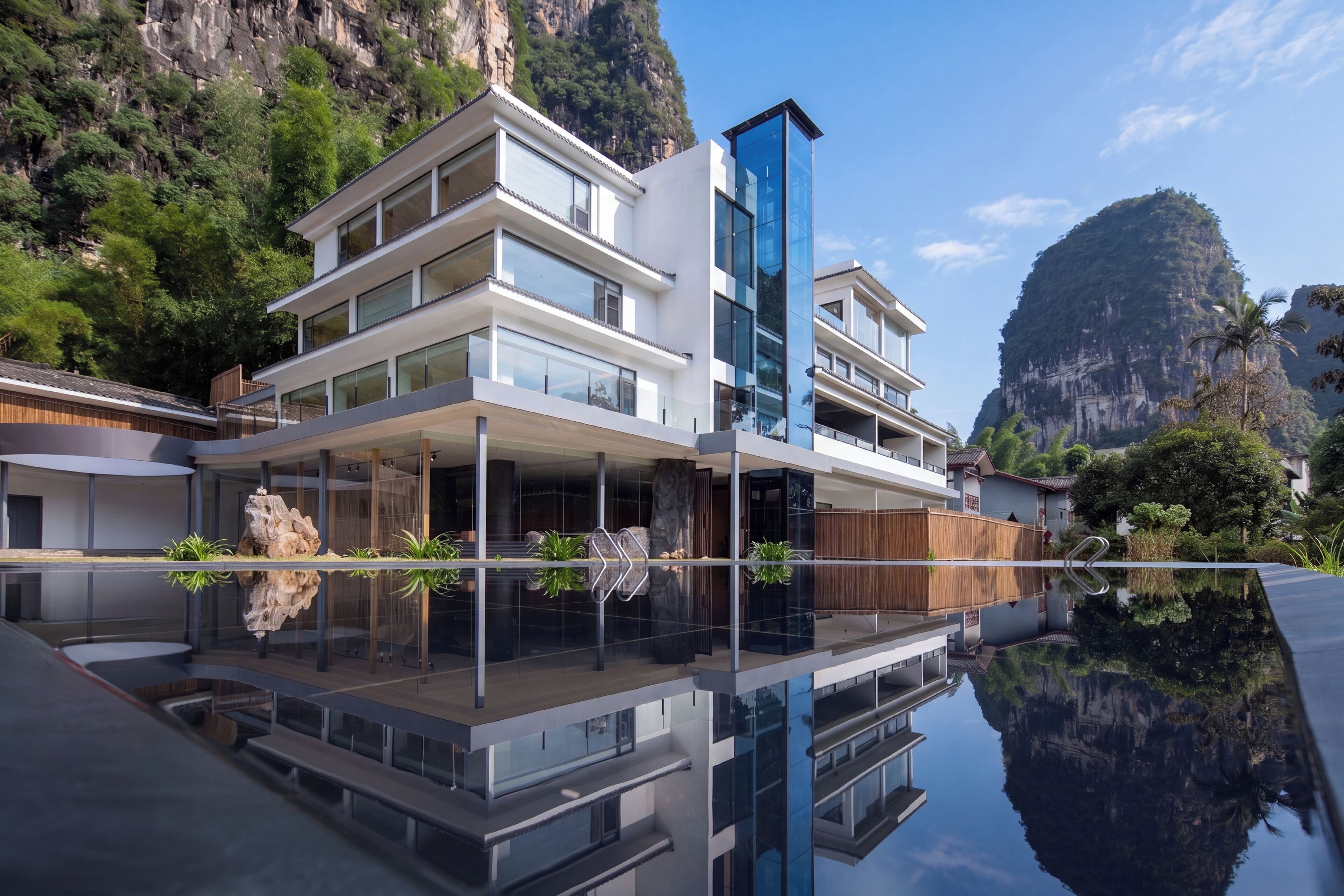 A modern multi-story building with a reflective pool in front, surrounded by natural scenery.