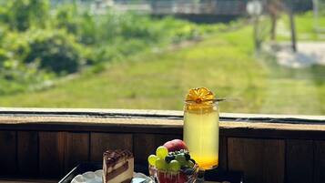 Un plateau de desserts avec une part de gâteau et un bol de fruits sur une table en bois, et un verre de boisson glacée au premier plan.