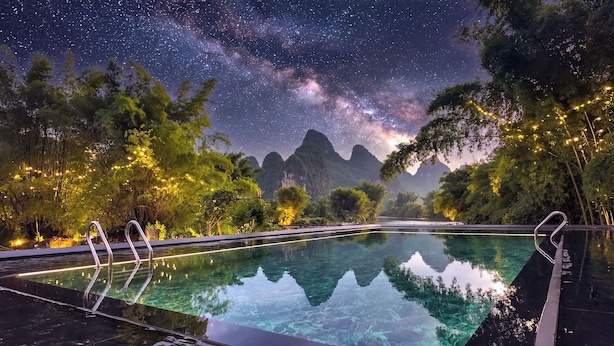 A pool with clear water reflecting trees and a starry night sky. - L'Eau Vive de Qixi Meidi Yangshuo- Riverfront Infinity Pool & Log Cabin Cafe (Guilin)