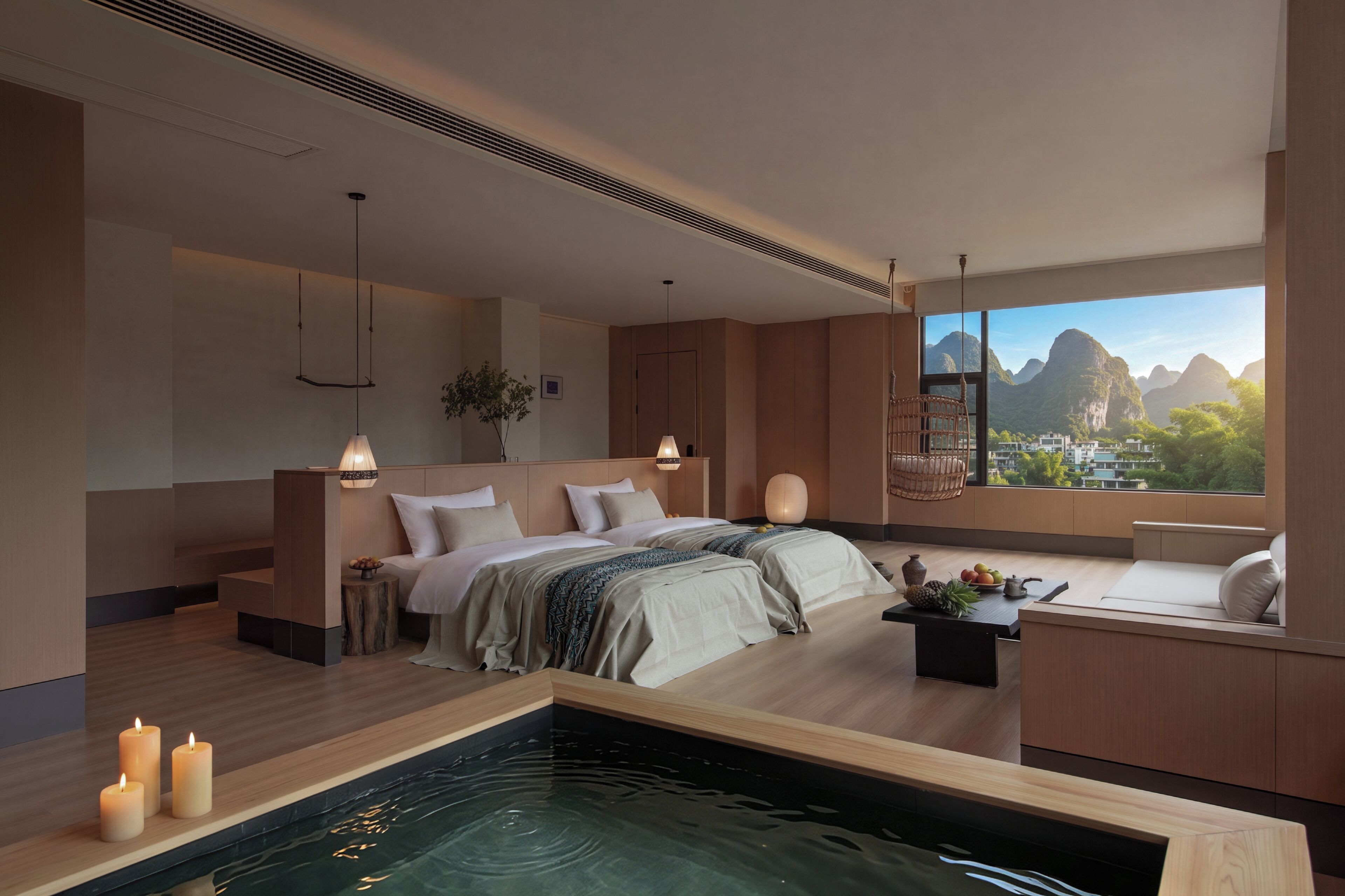 A modern bedroom with a large bed, bedside tables, a small sitting area, a view of mountains, and a water feature.
