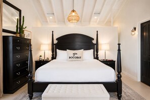 Un dormitorio ordenado con una cama grande, lámparas de noche, un aparador y una lámpara colgante.
