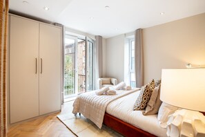 Ein Schlafzimmer mit Bett, Kleiderschrank, Stuhl und einem Fenster mit Vorhängen.